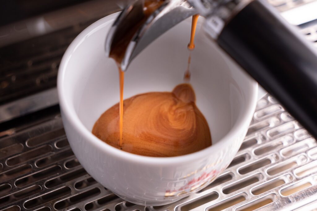 Fresh espresso shot with crema being extracted into glass cups